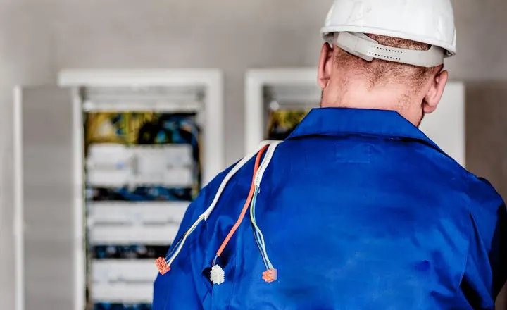 Électricien avec casque de chantier intervenant sur un tableau électrique