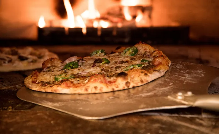 Pizza sortant d'un four à bois